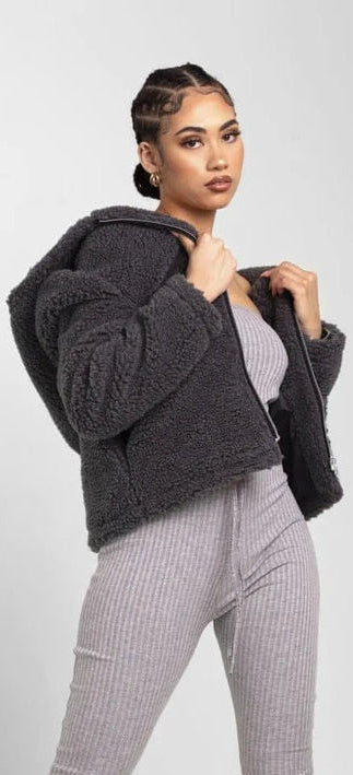 Woman wearing a dark gray fleece jacket with a white background