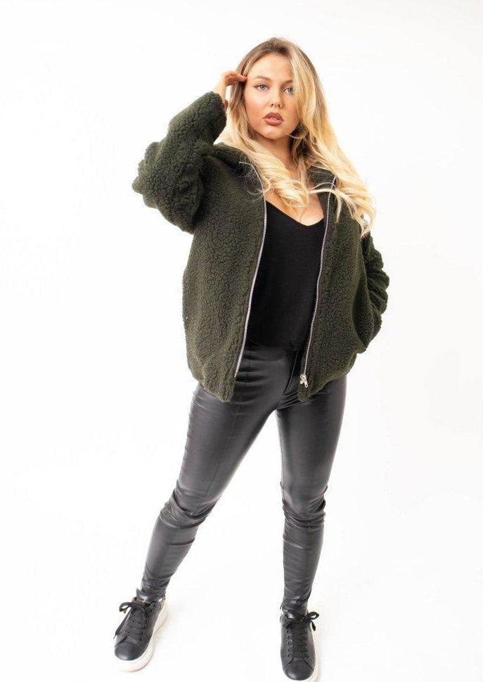 Woman wearing a green fleece jacket and black pants on a white background