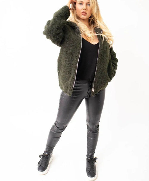 Woman wearing a green fleece jacket and black pants on a white background