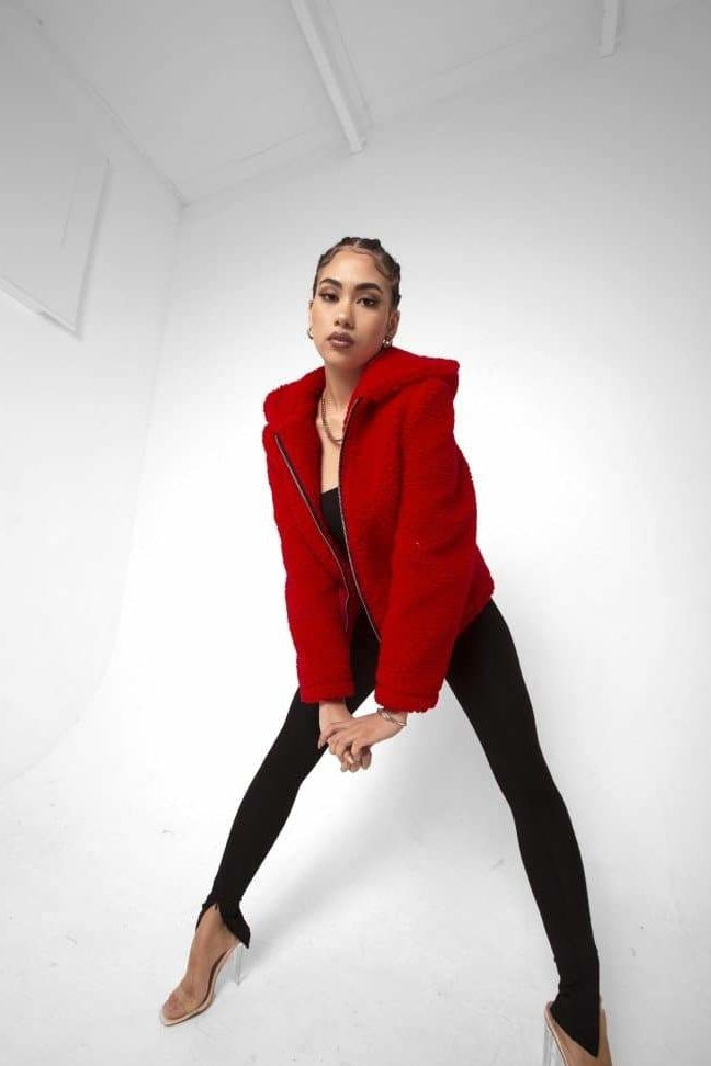 Person wearing a red jacket and black pants on a white background
