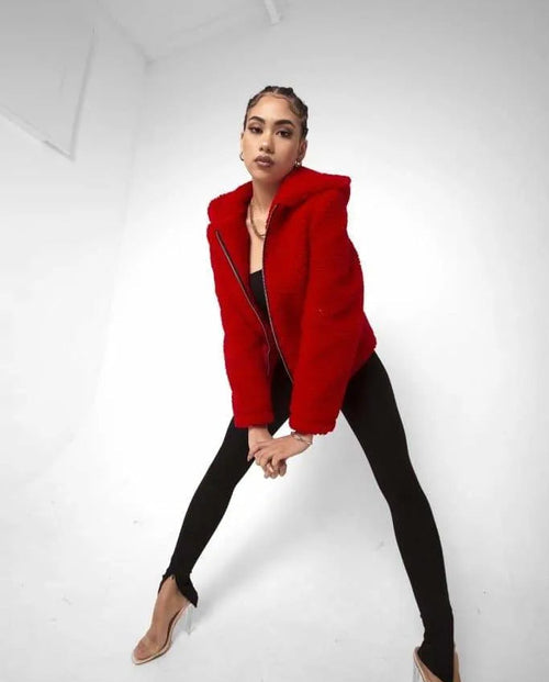 Person wearing a red coat and black pants on a white background