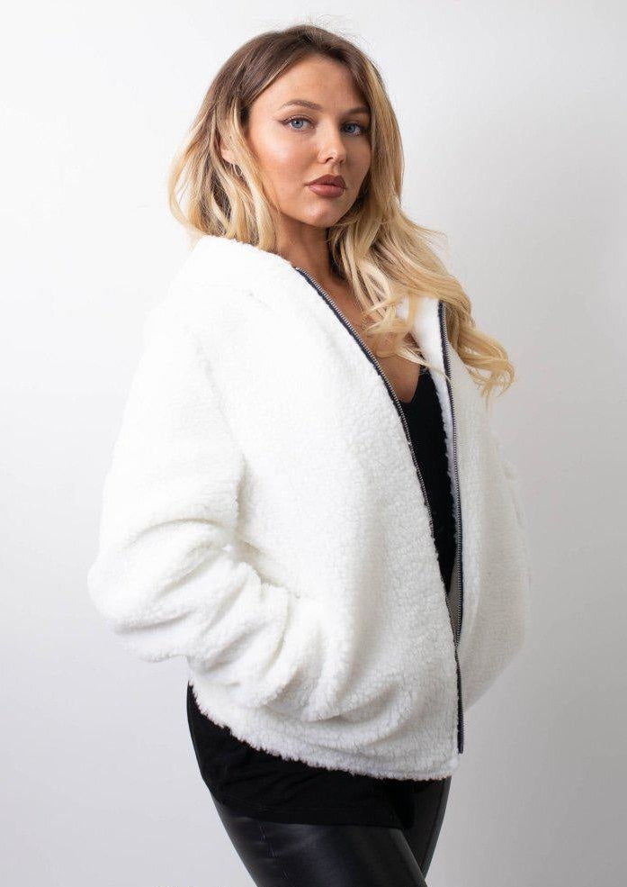 Woman wearing a white fluffy cardigan against a plain background