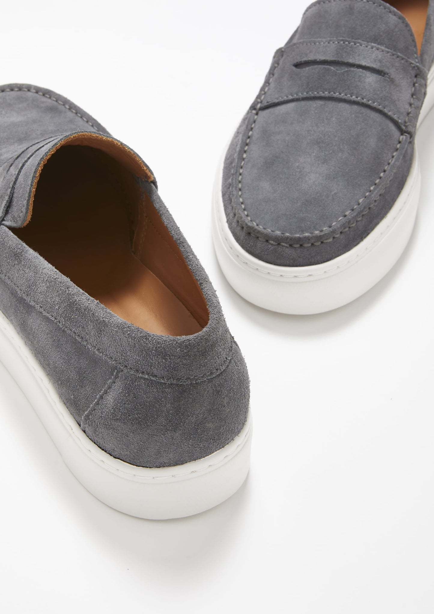 Gray suede loafers with white soles on a light gray background