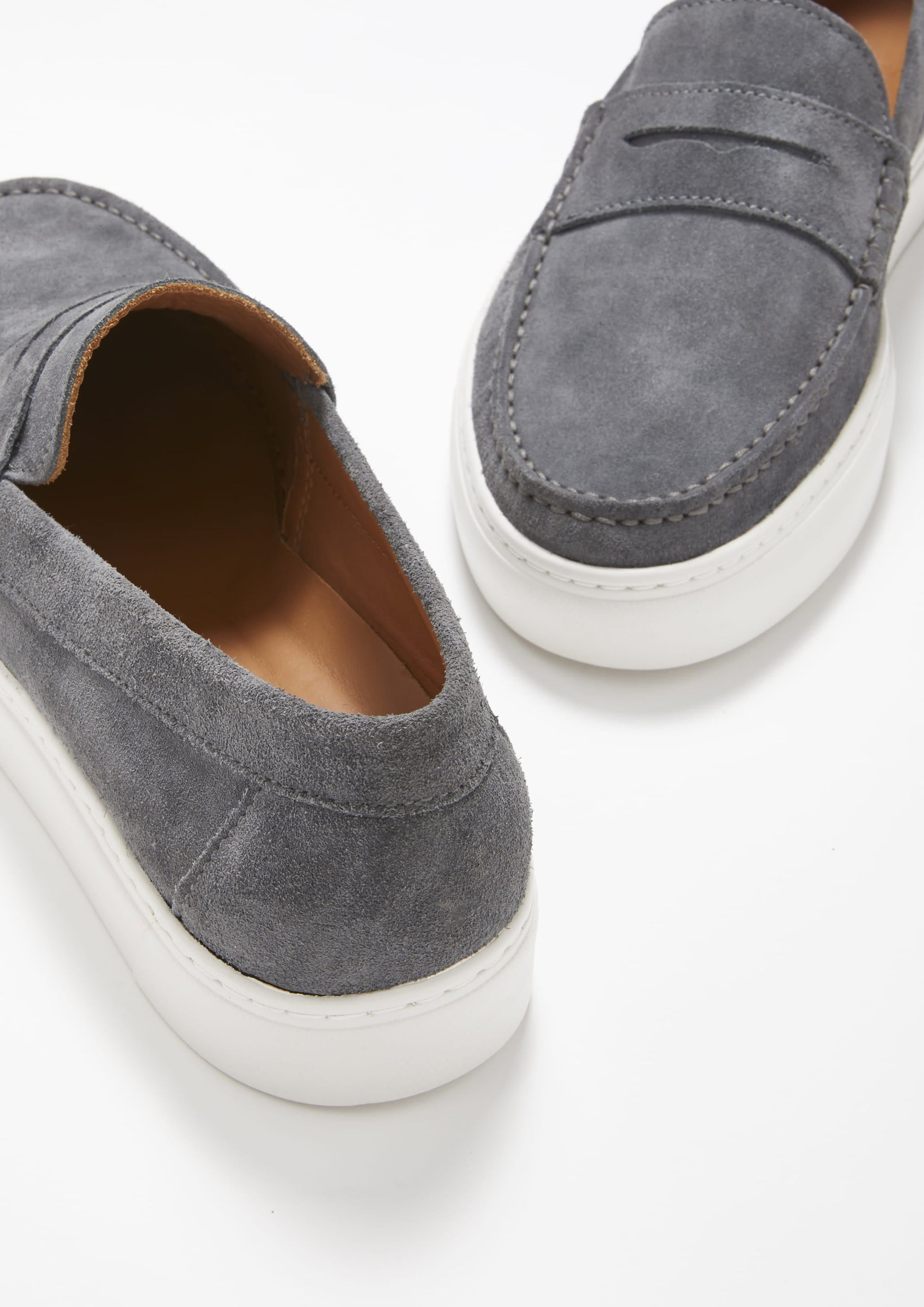 Gray suede loafers with white soles on a light gray background