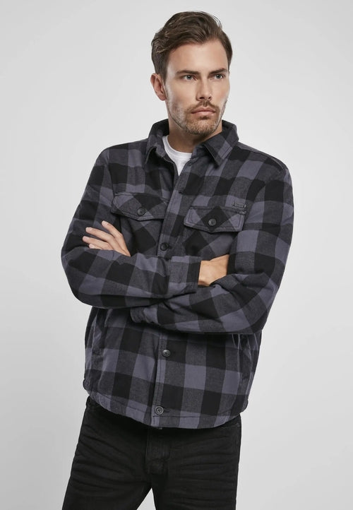 Man wearing a black and gray plaid shirt against a white background
