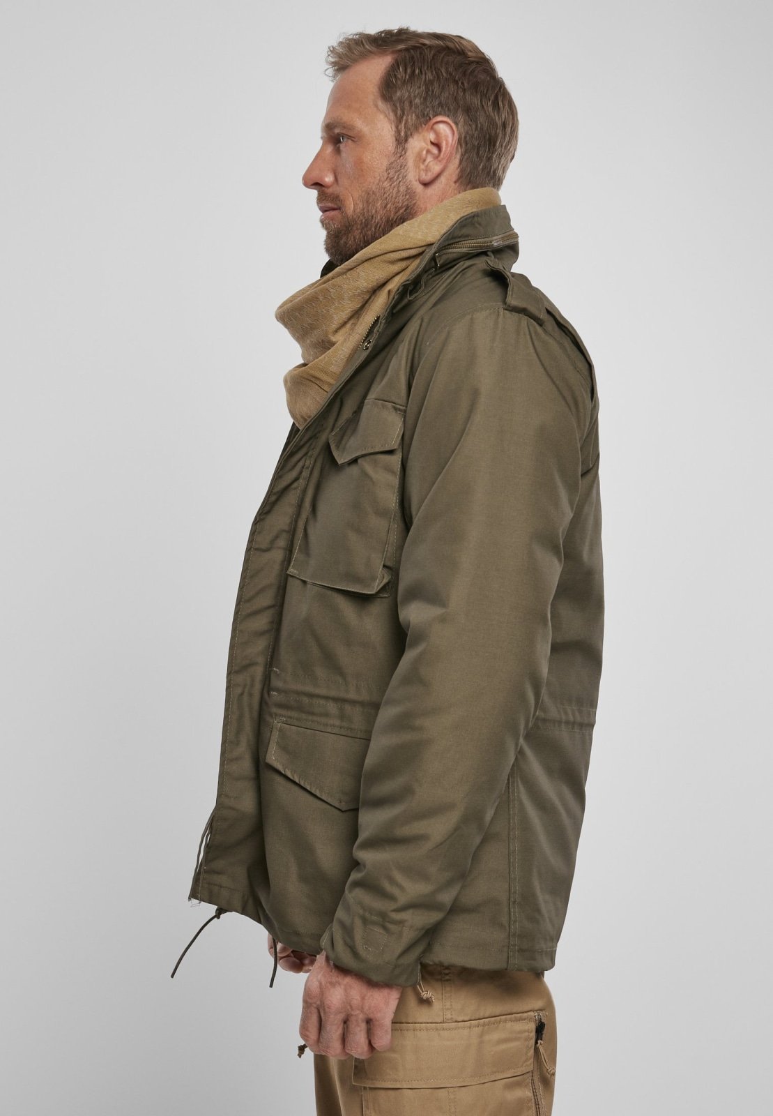 Man wearing a green jacket and beige scarf on a white background