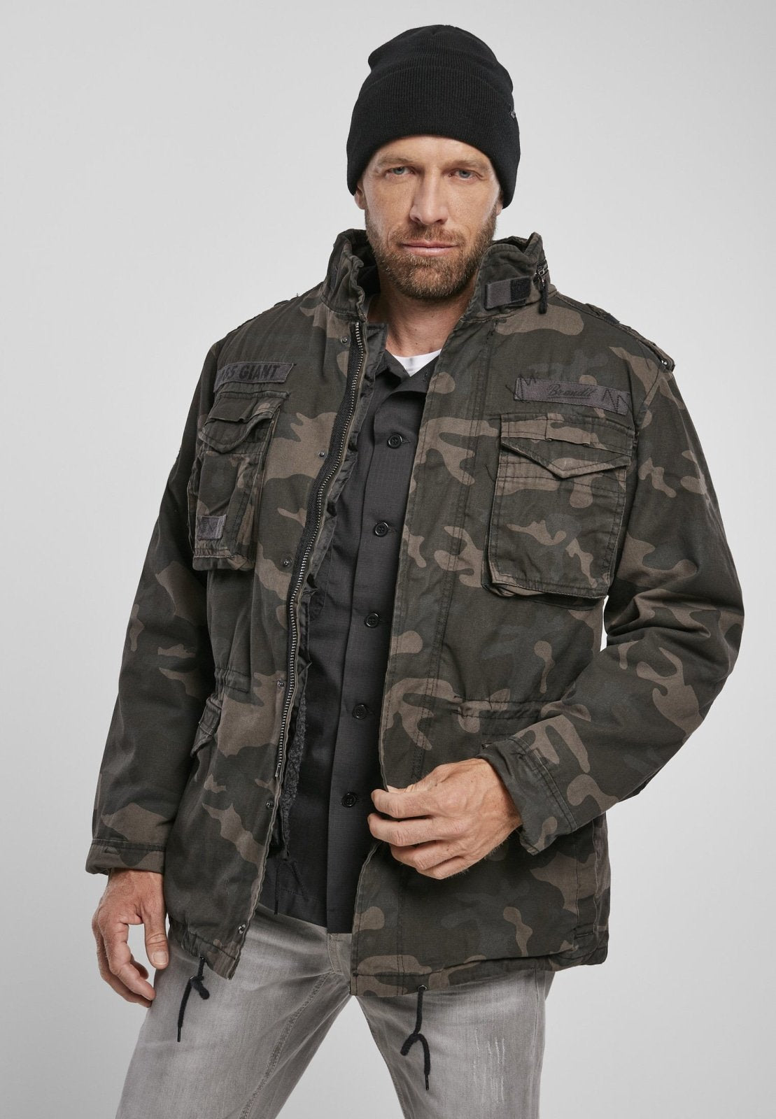 Man wearing a camouflage jacket and black beanie on a gray background
