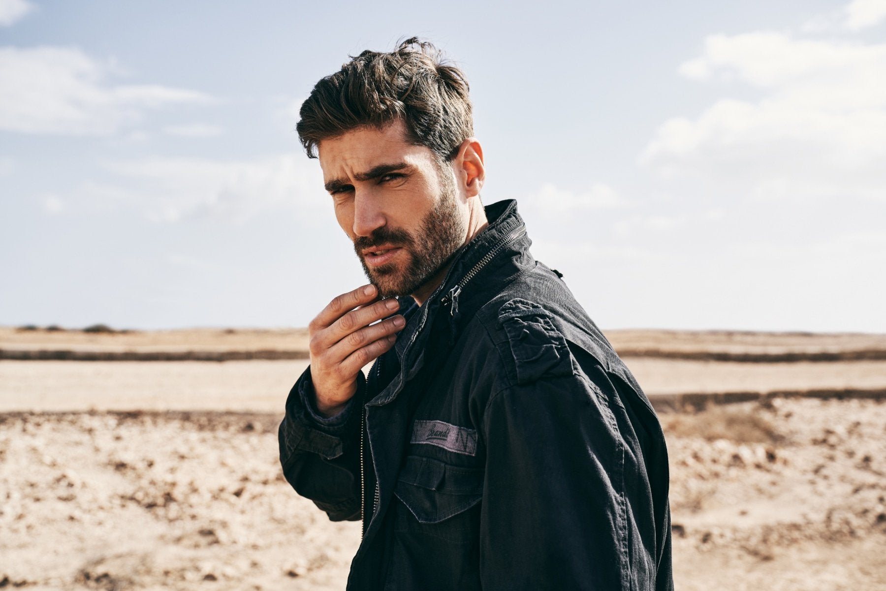 Man wearing a black jacket in a desert landscape
