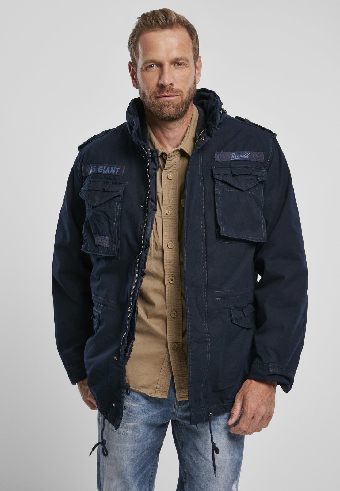 Man wearing a navy jacket with visible branding on a plain background