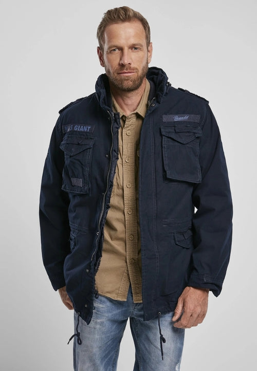 Man wearing a navy jacket with visible branding on a plain background