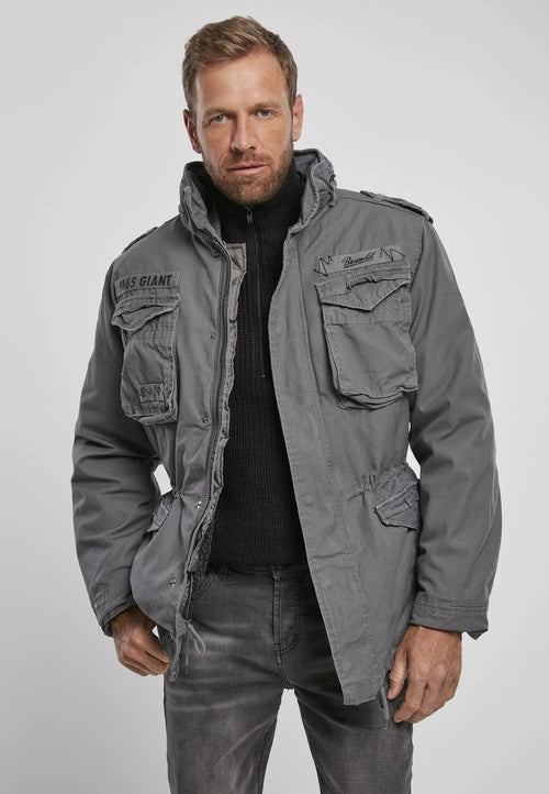 Man wearing a gray jacket with multiple pockets on a plain background