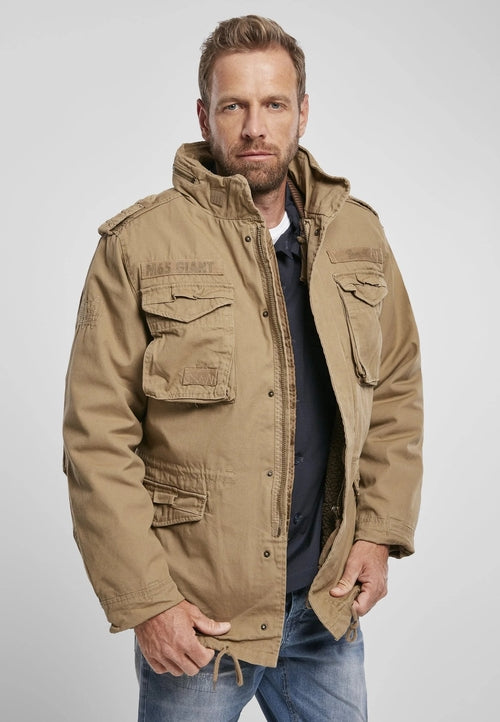 Man wearing a tan field jacket on a plain background