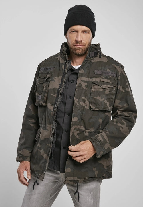 Man wearing a camouflage jacket and black beanie on a gray background