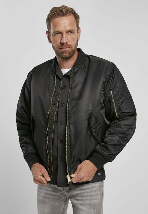Man wearing a black bomber jacket on a plain background