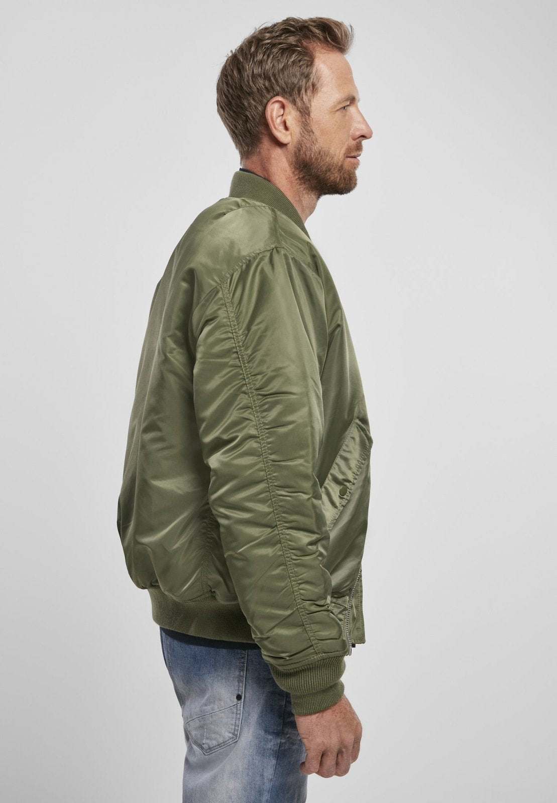 Man wearing a green bomber jacket on a light gray background