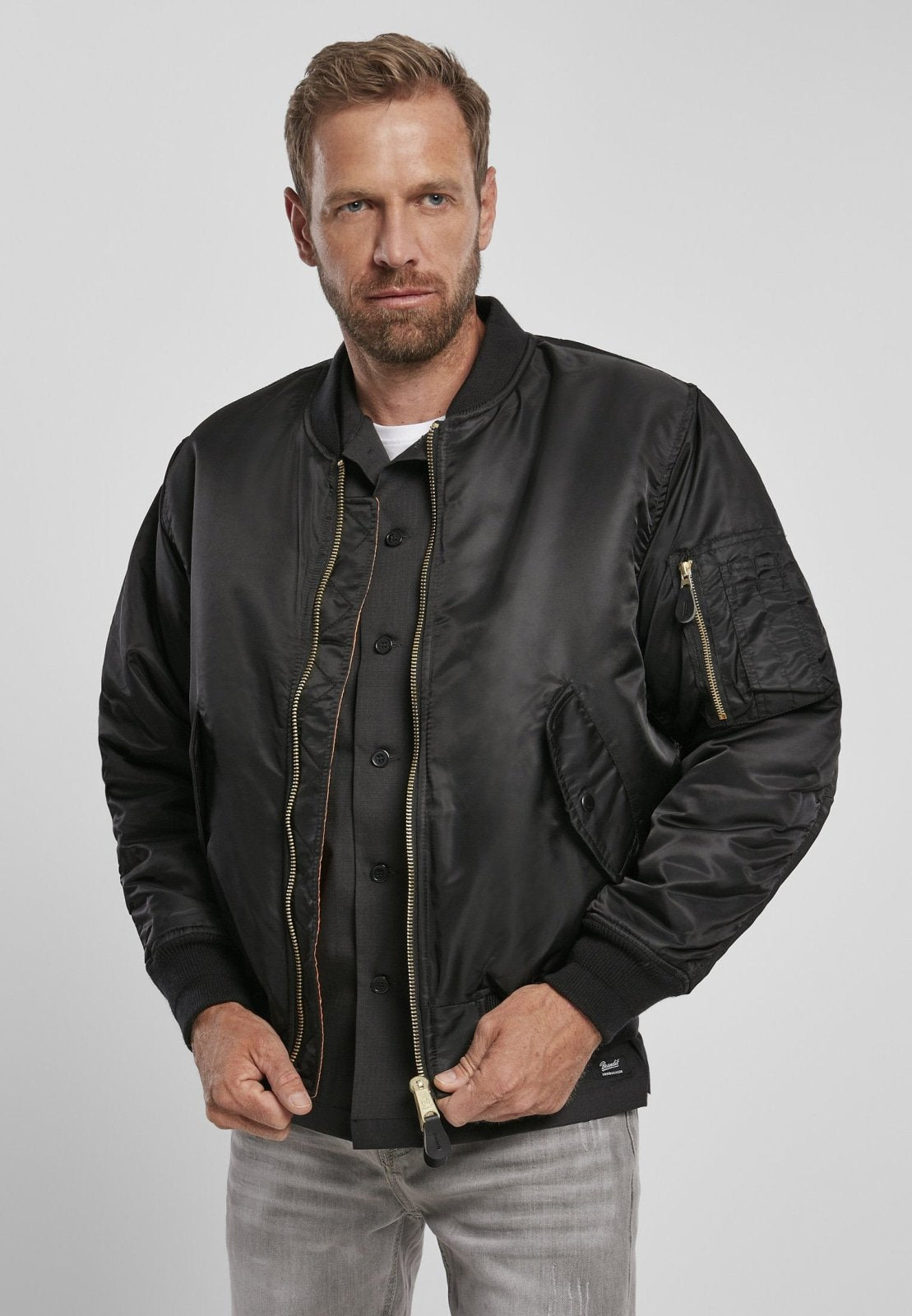 Man wearing a black bomber jacket on a plain background