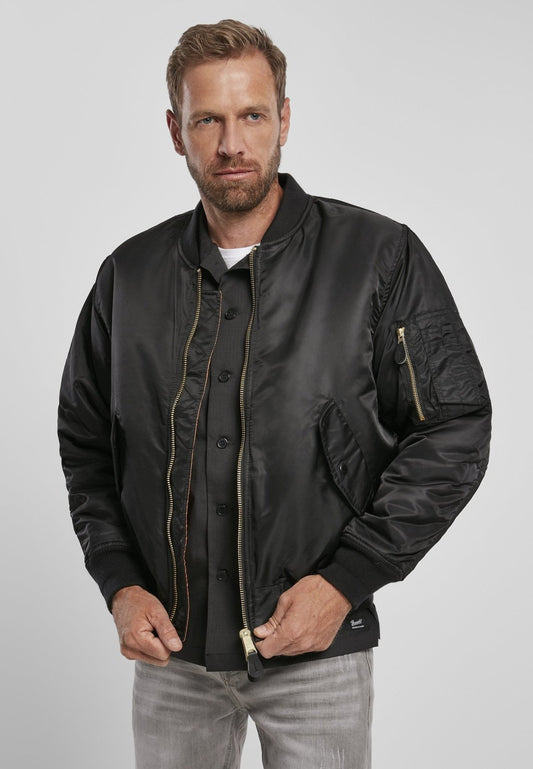Man wearing a black bomber jacket on a plain background