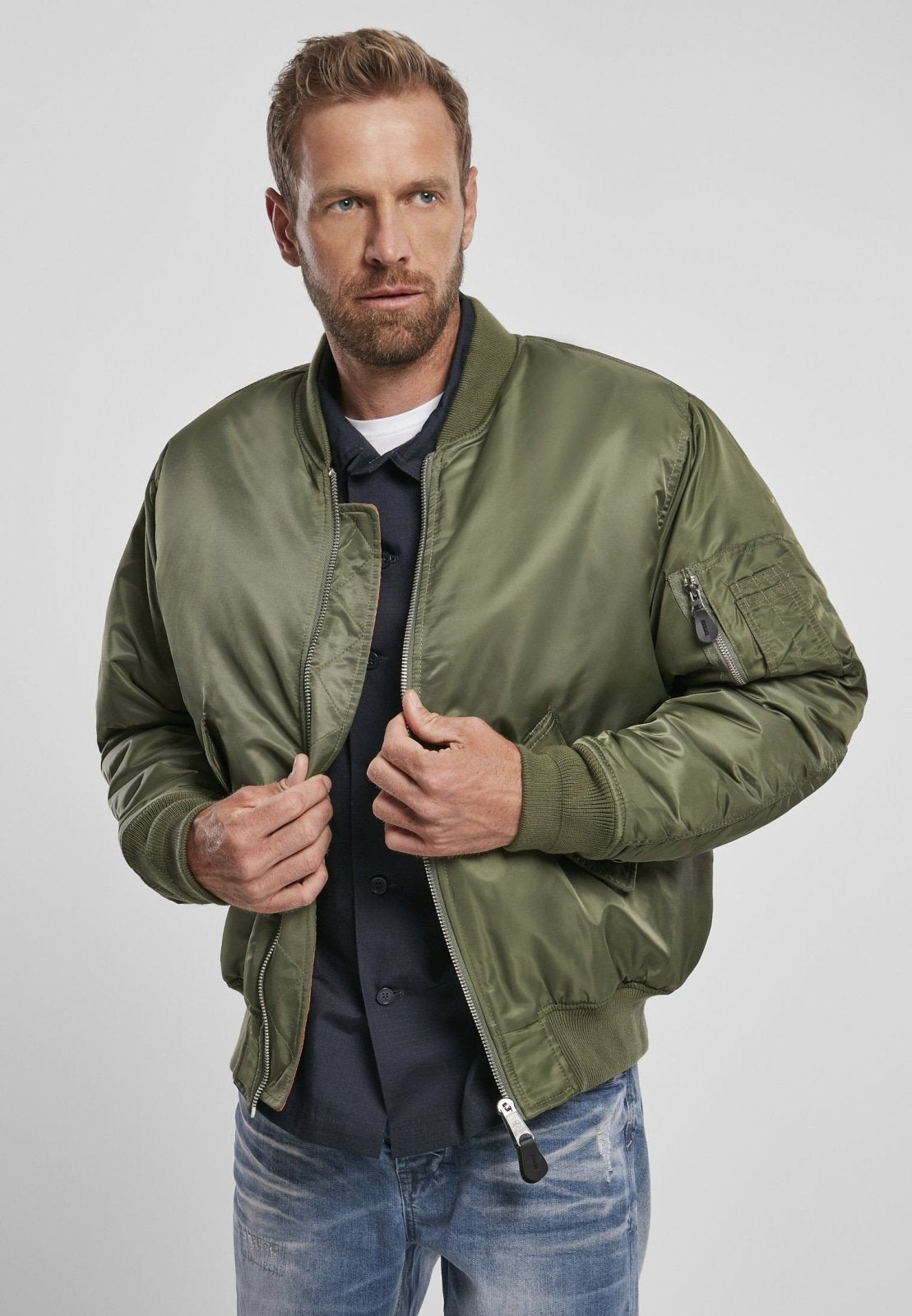 Man wearing a green bomber jacket on a light gray background