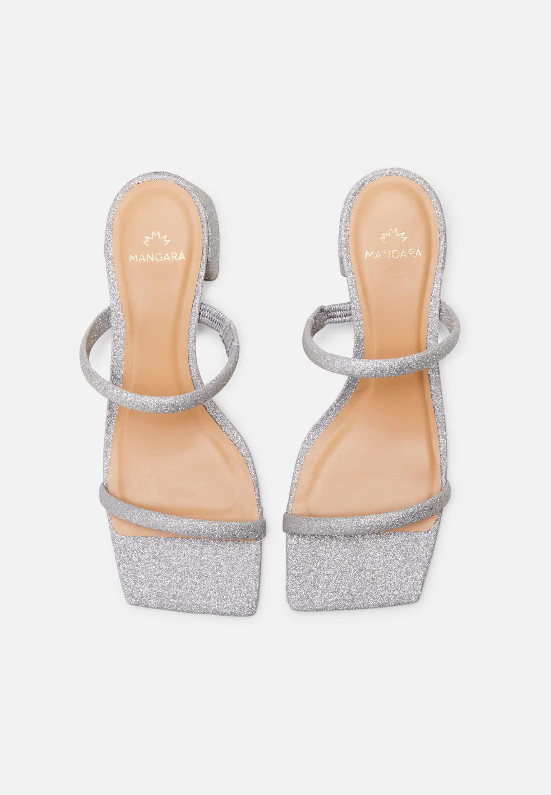 Pair of silver glitter high-heeled sandals on a light gray background