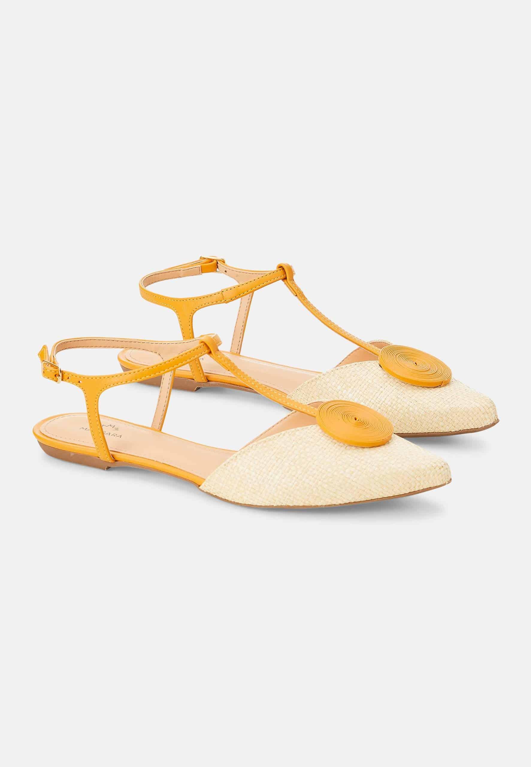 Pair of yellow strappy flats on a white background
