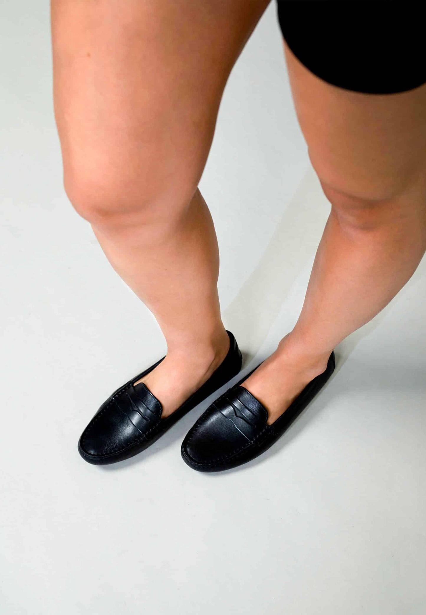 Person wearing black loafers on a plain background