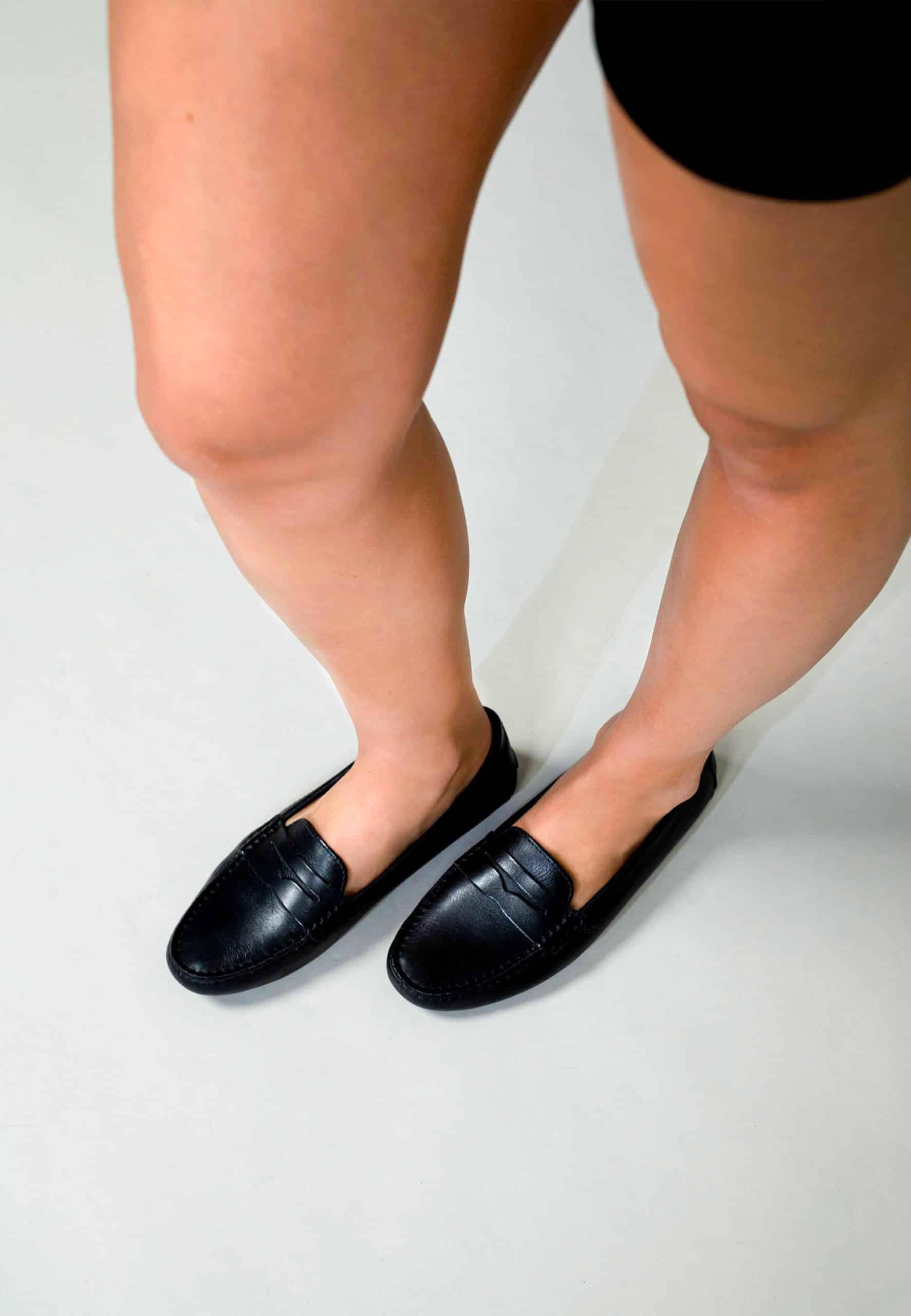 Person wearing black loafers on a plain background