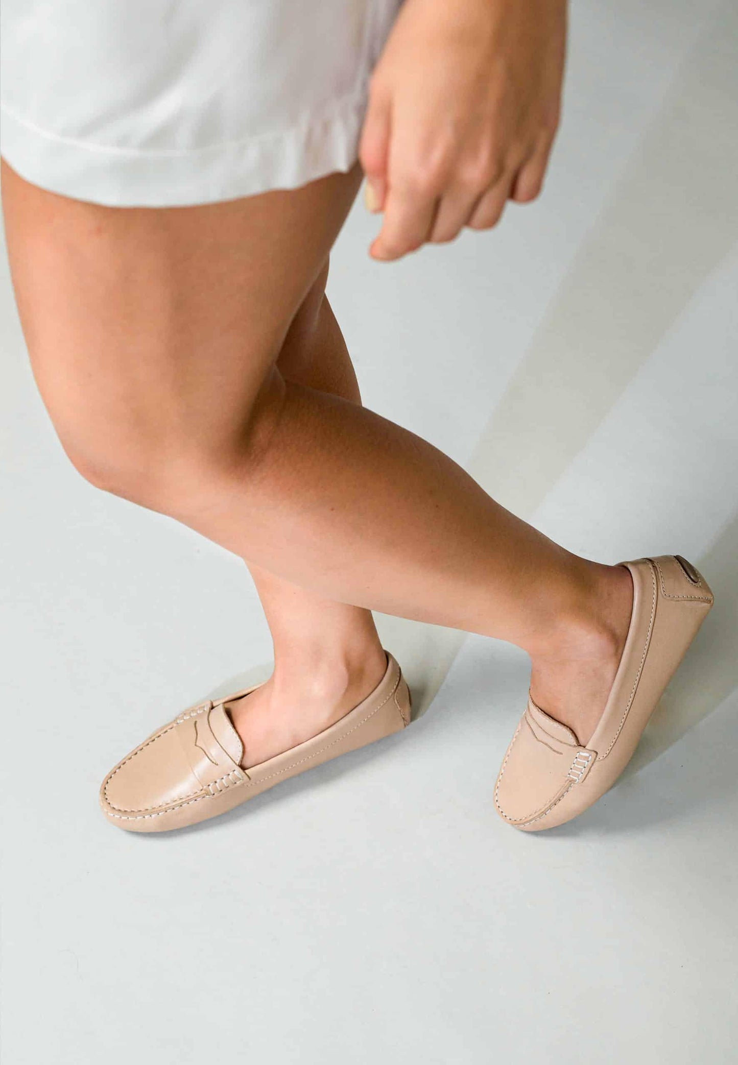 Person wearing beige loafers on a plain background