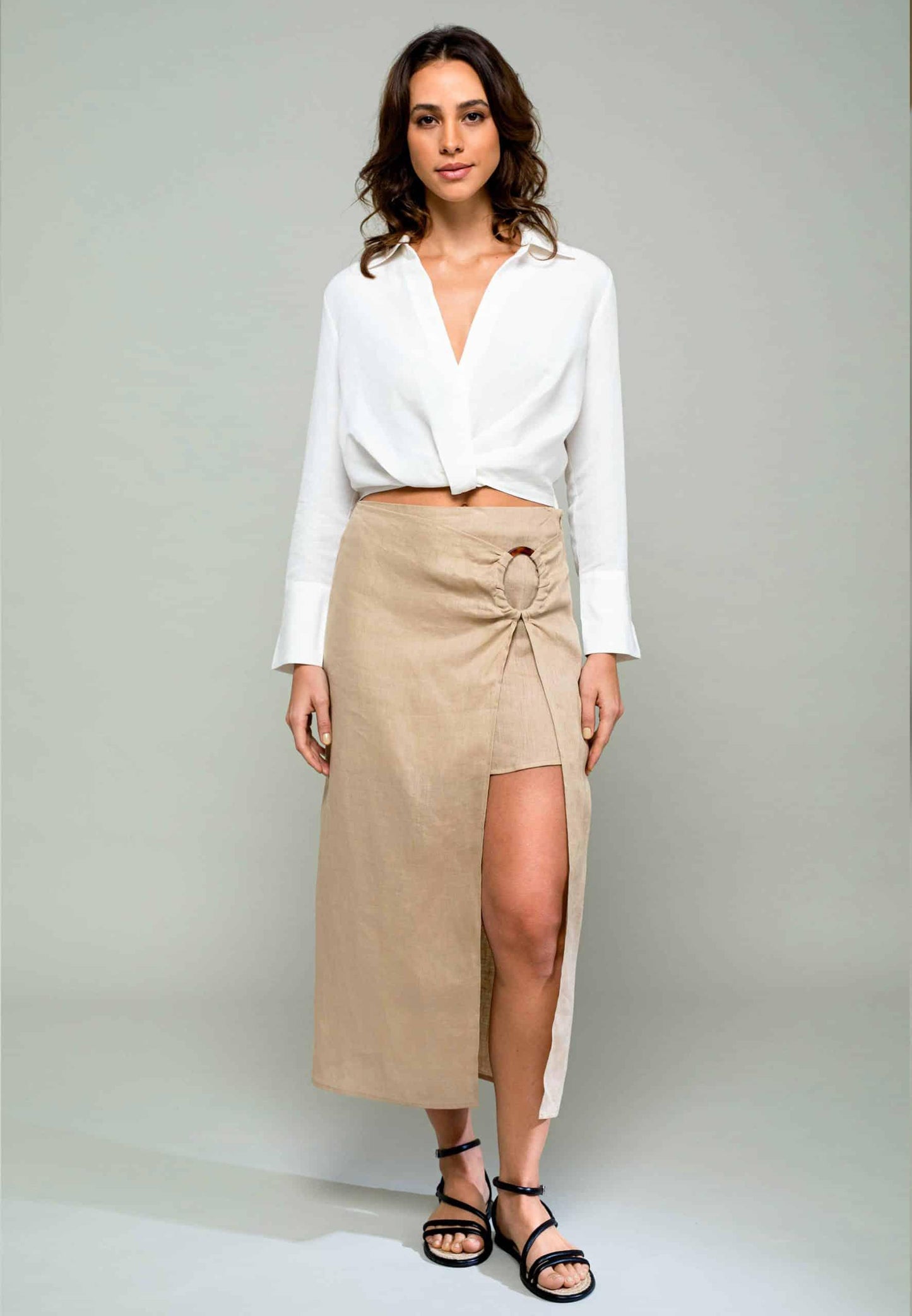 Woman wearing a white blouse and beige skirt on a plain background