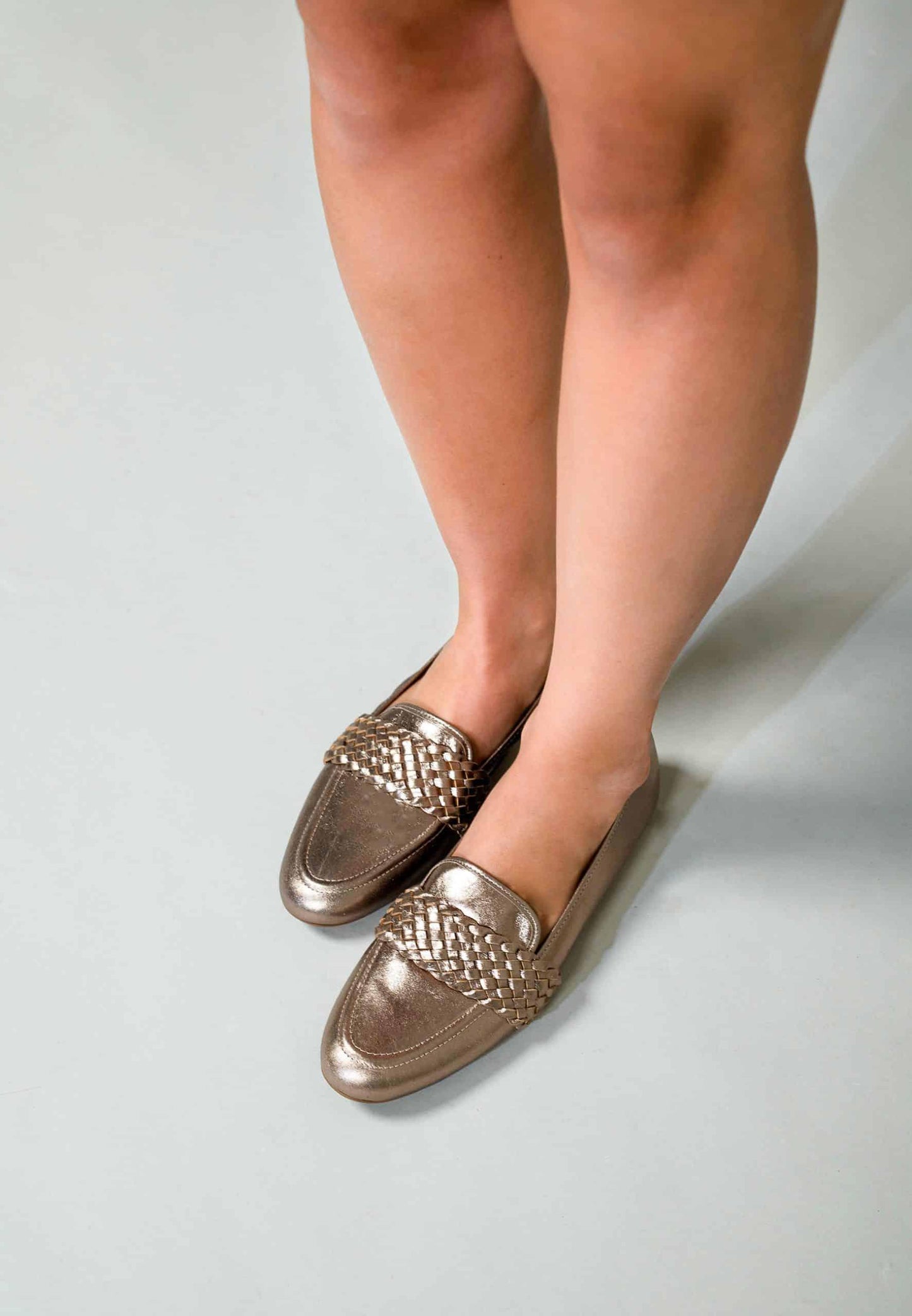 Person wearing metallic loafers on a plain background