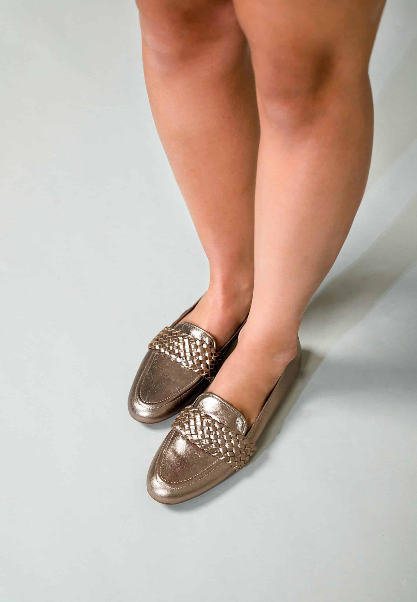 Person wearing metallic loafers on a plain background