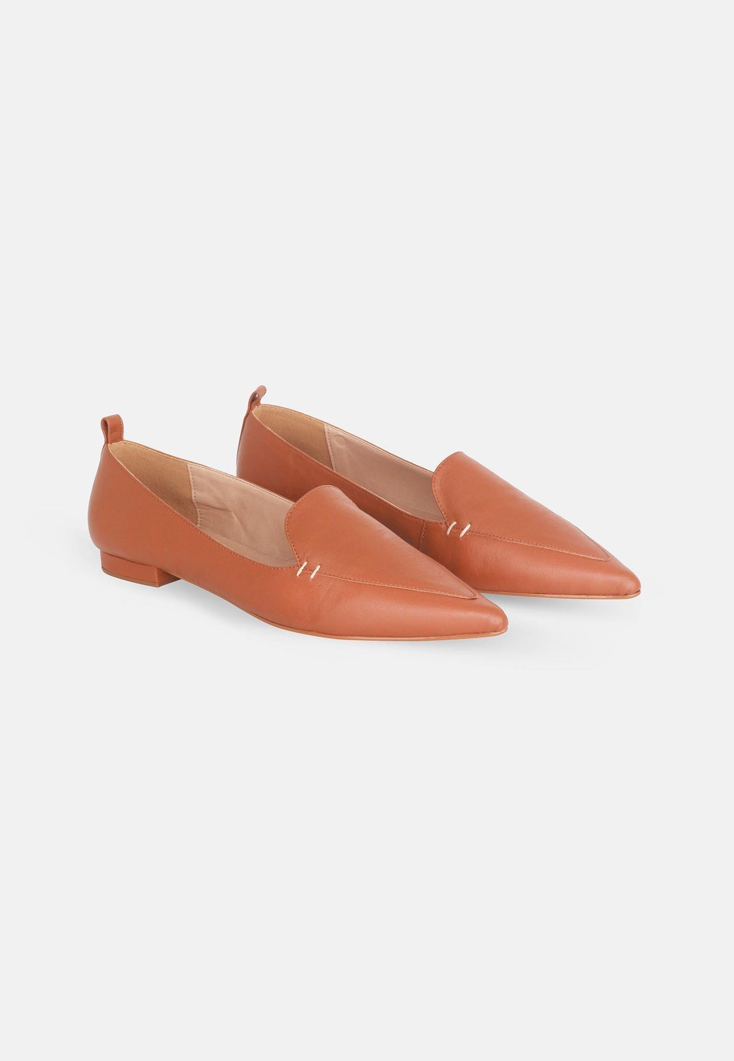 Pair of orange pointed-toe flats on a light gray background
