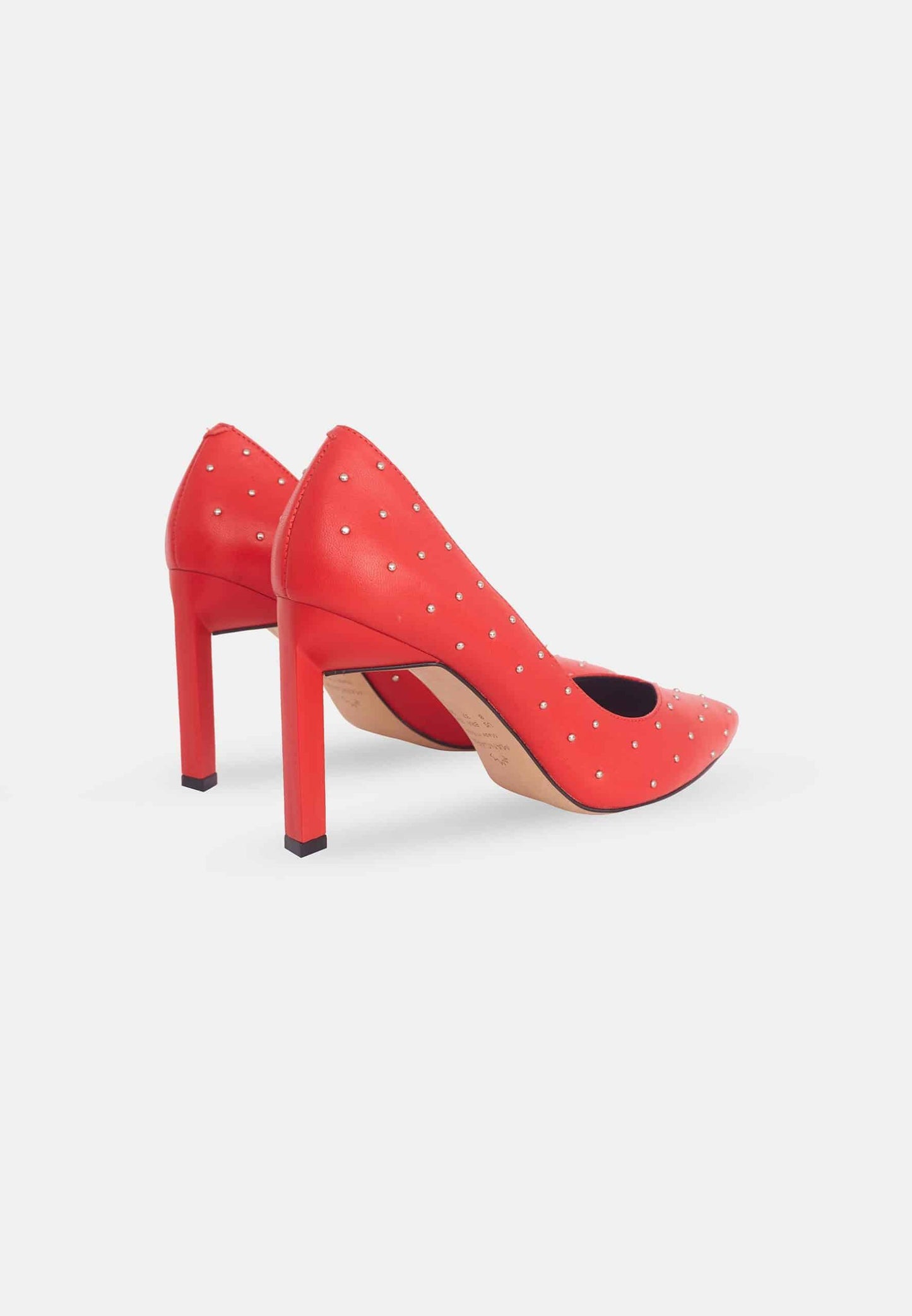 Red high-heeled shoes with studded details on a white background