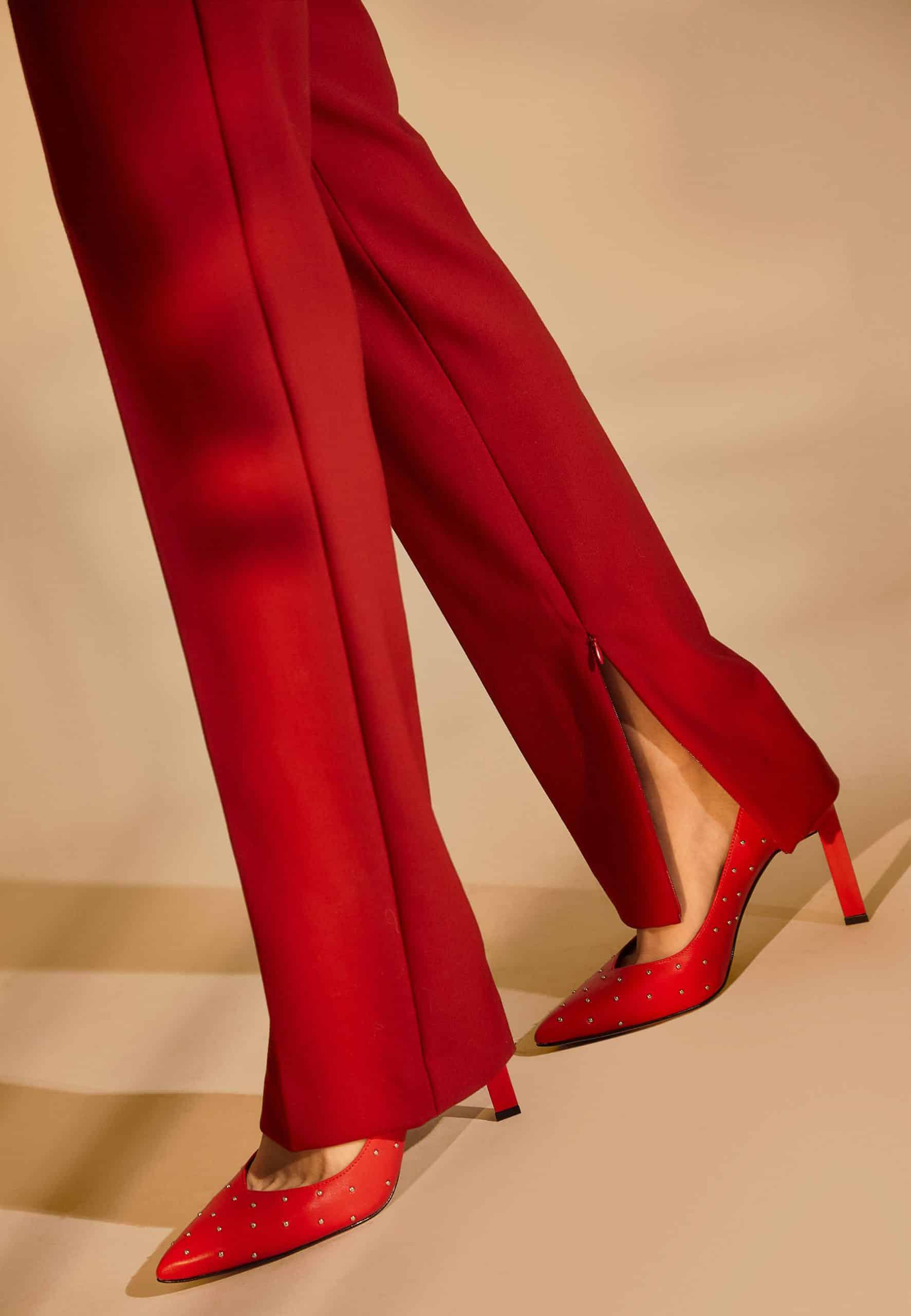 Red high-waisted pants and red high-heeled shoes on a beige background