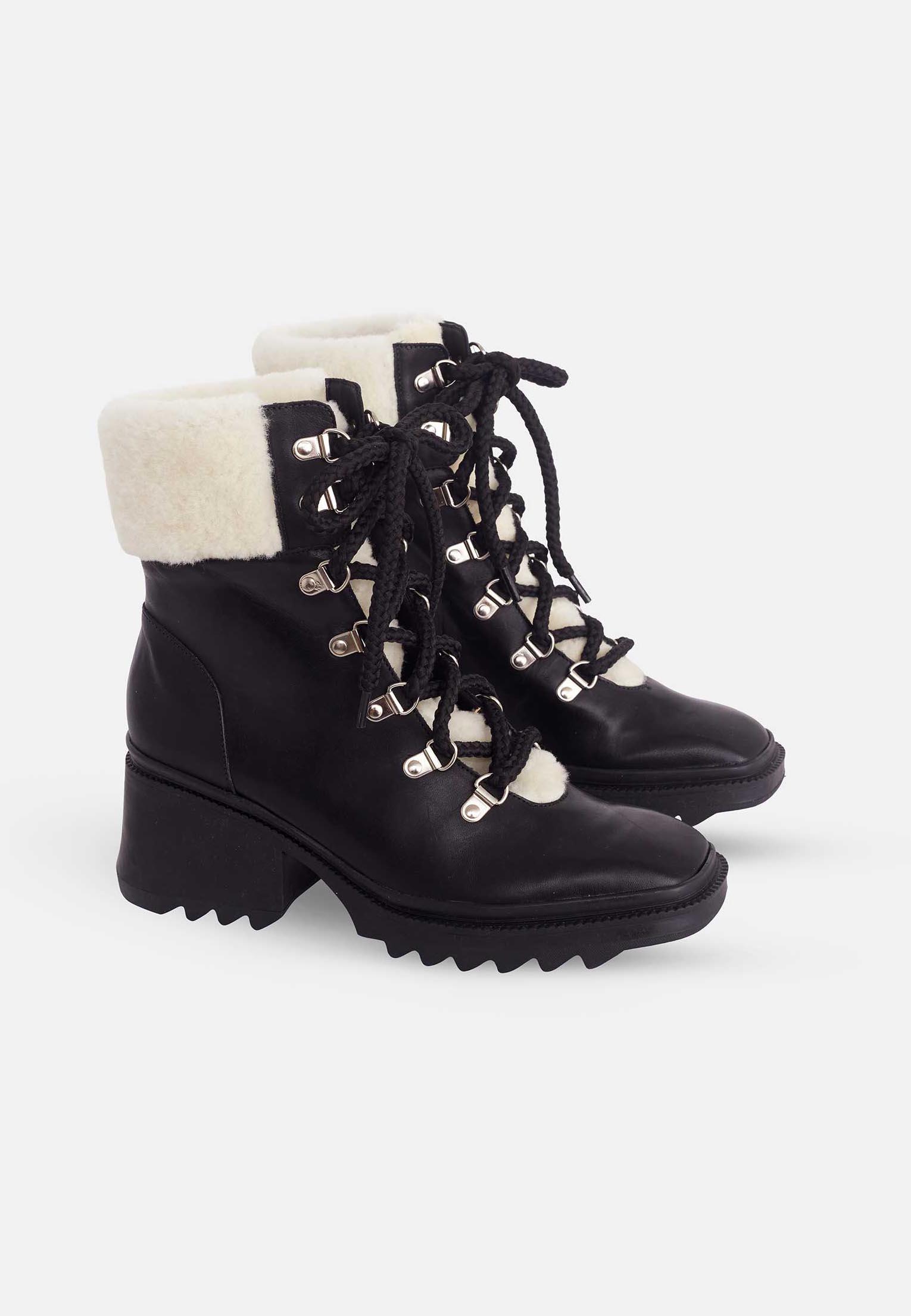 Black lace-up boots with white fur lining on a white background