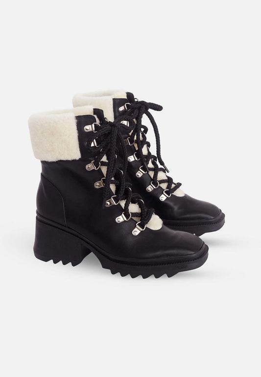 Black lace-up boots with white fur lining on a white background