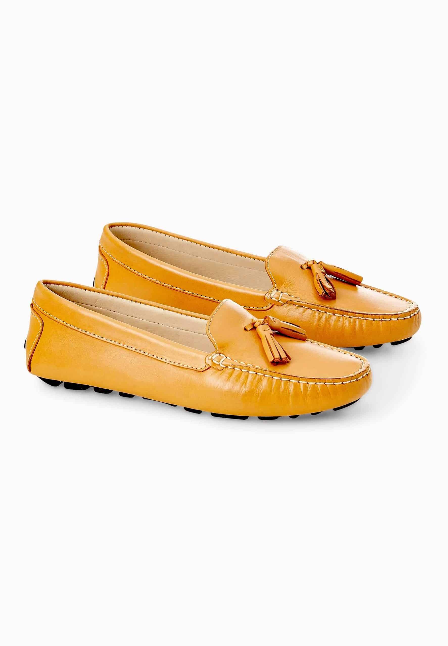 Pair of yellow loafers with tassels on a white background