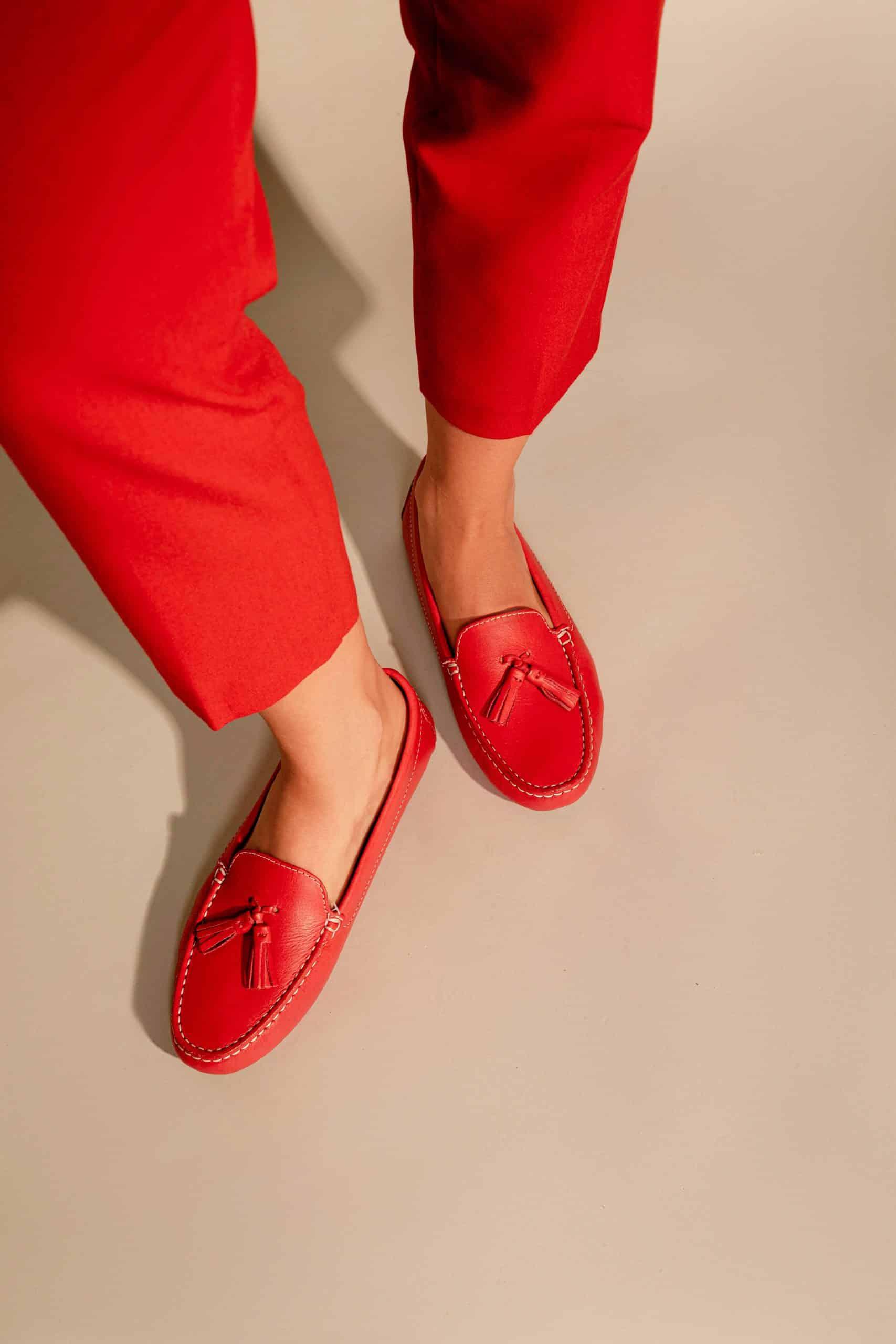 Red loafers worn with red pants on a beige background