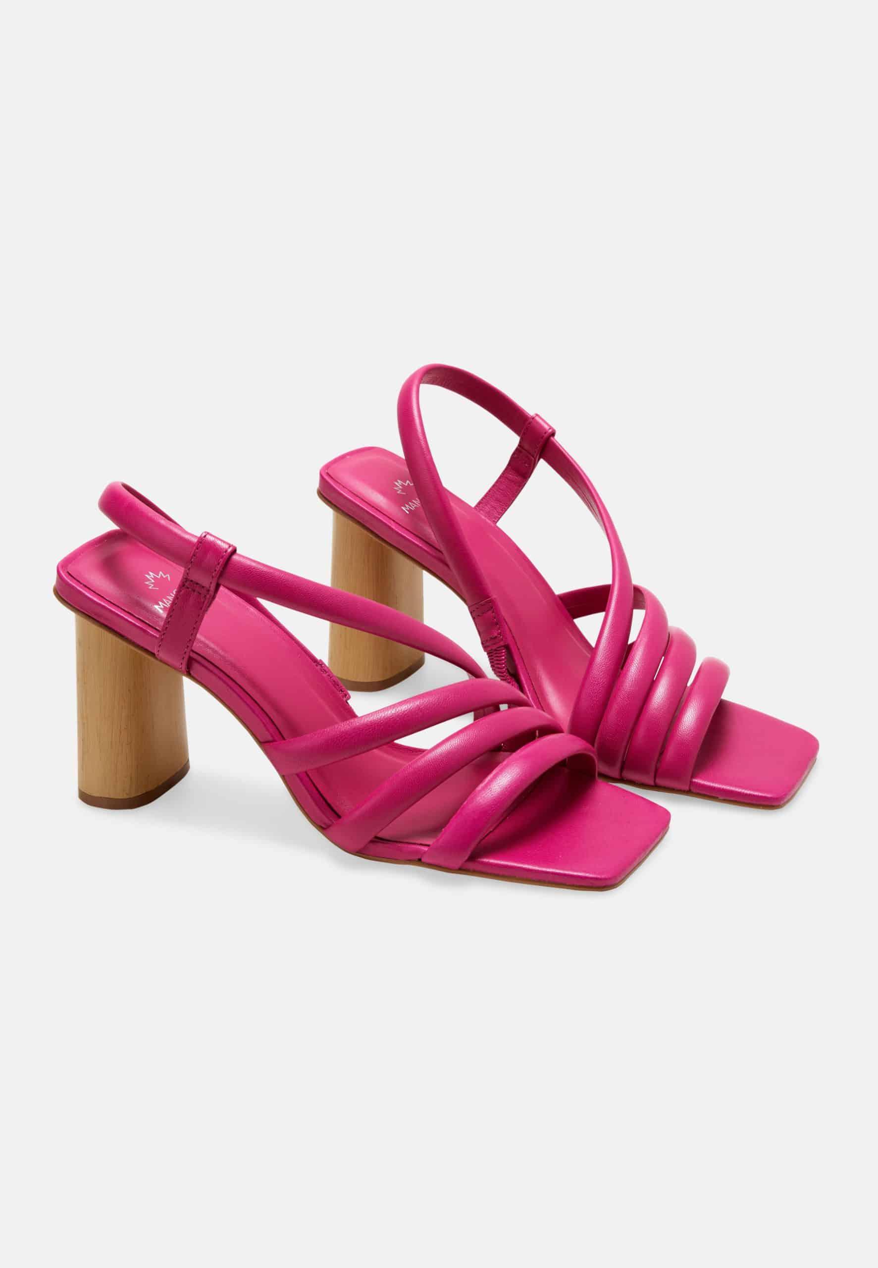 Pair of bright pink high-heeled sandals on a light gray background