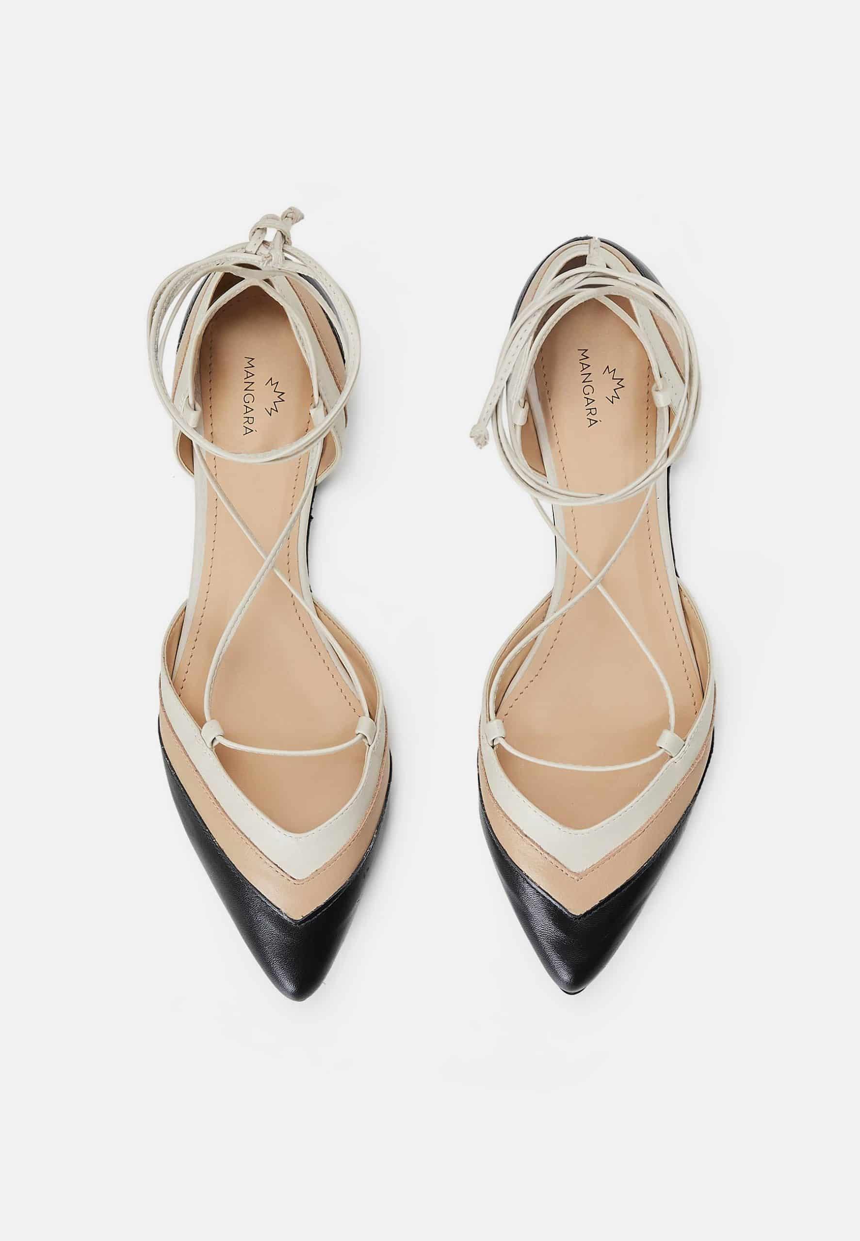 Pair of strappy high-heeled shoes with black and beige design on a white background