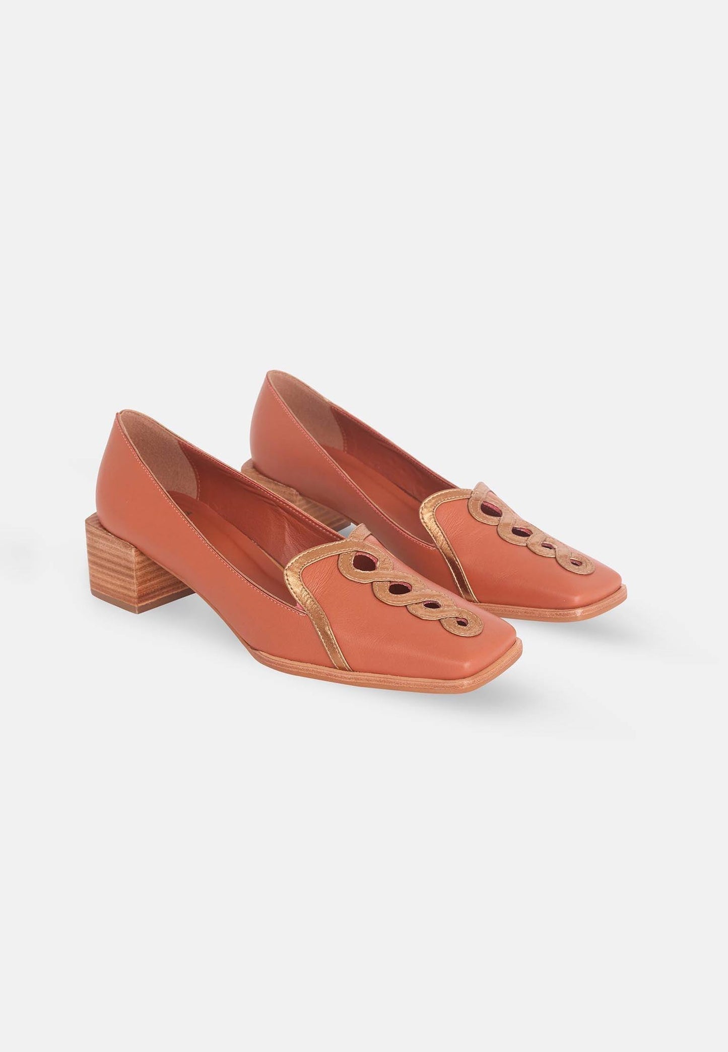 Pair of orange shoes with wooden block heel on a light gray background
