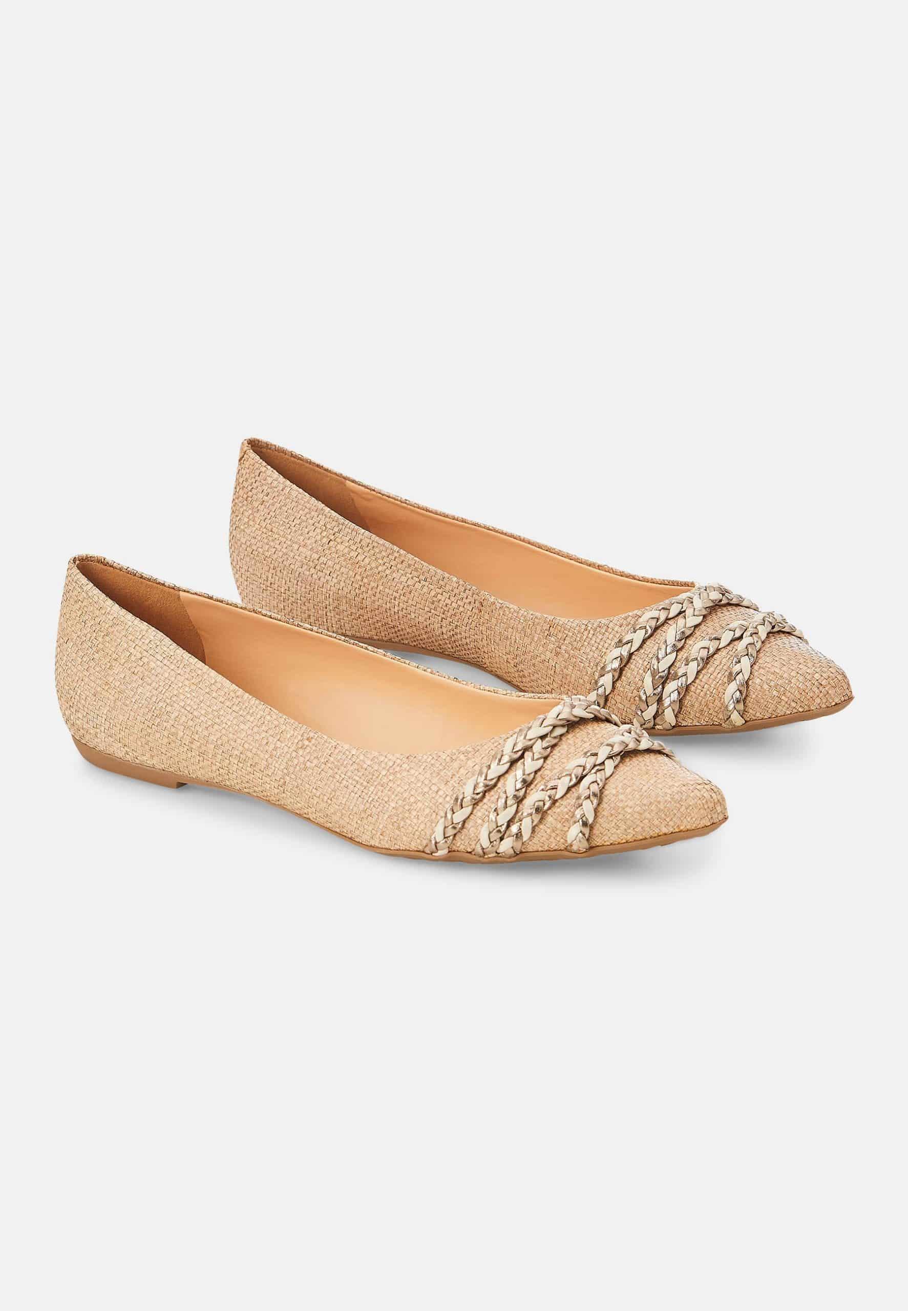 Pair of gold flats with decorative straps on a white background