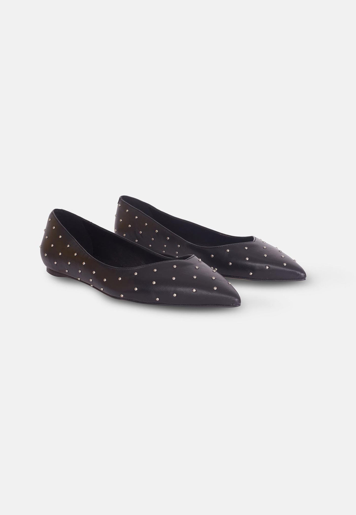 Pair of black pointed-toe flats with white polka dots on a white background