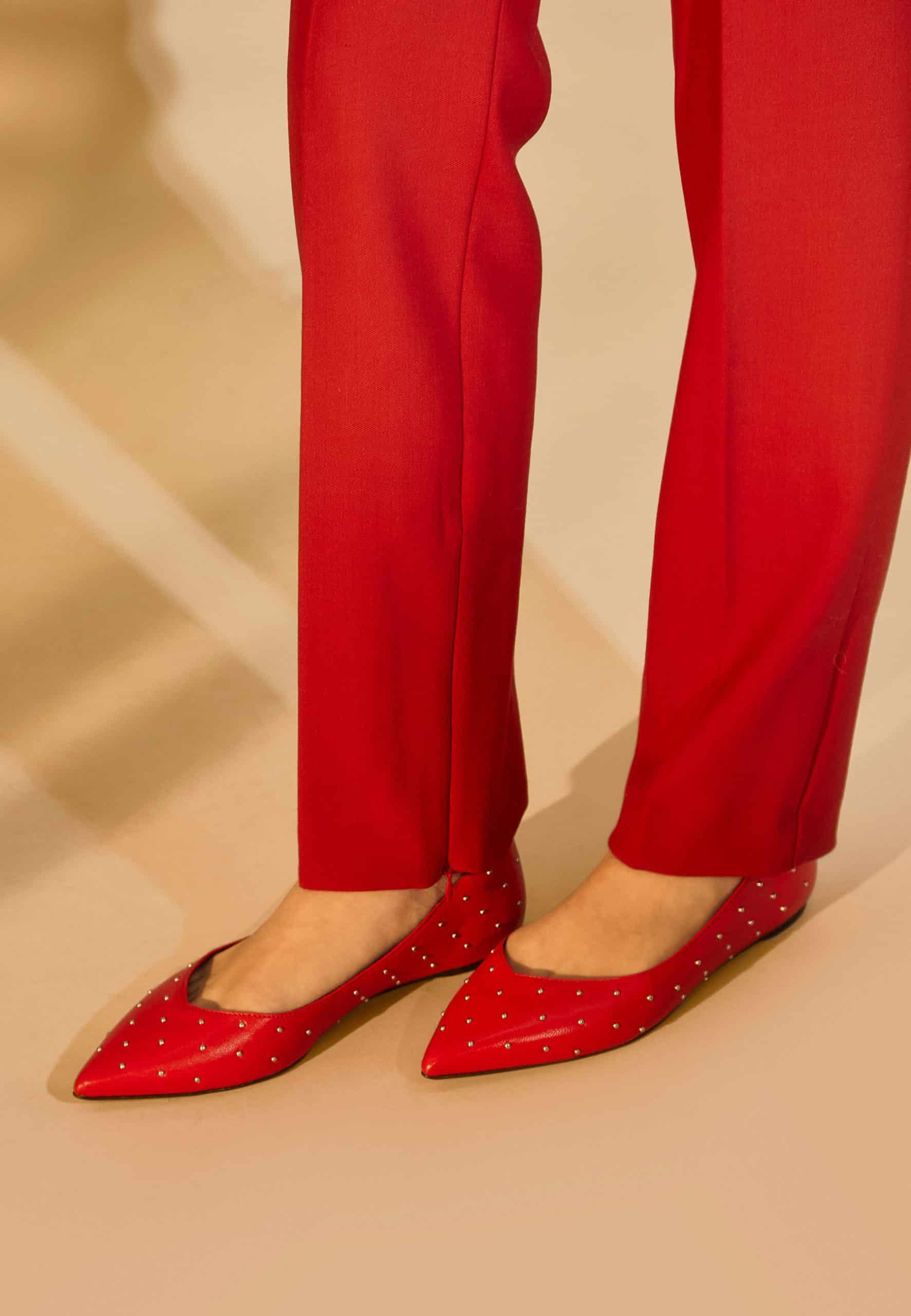 Red pants and red pointed-toe shoes on a beige background