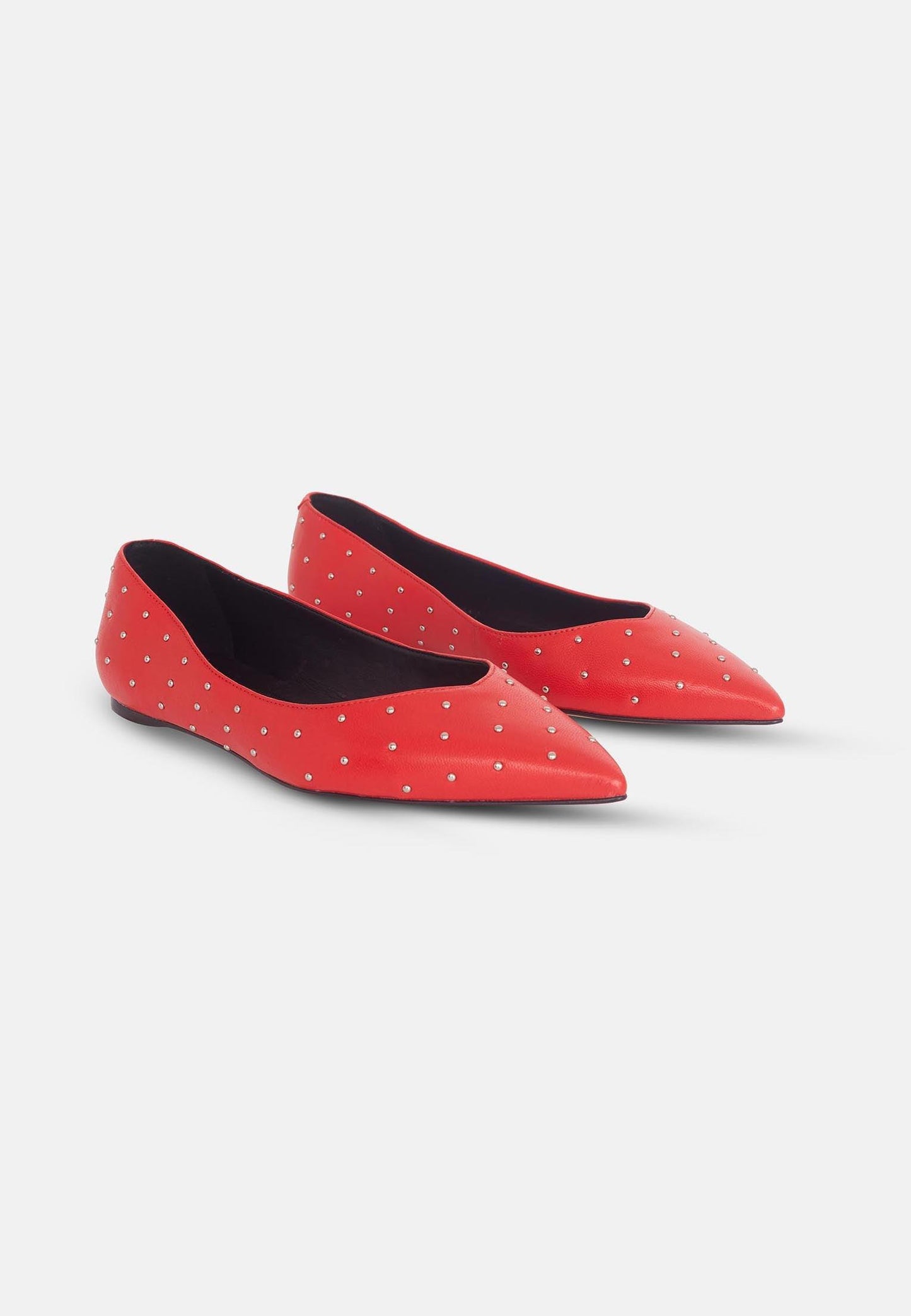 Red pointed-toe flats with white polka dots on a light gray background