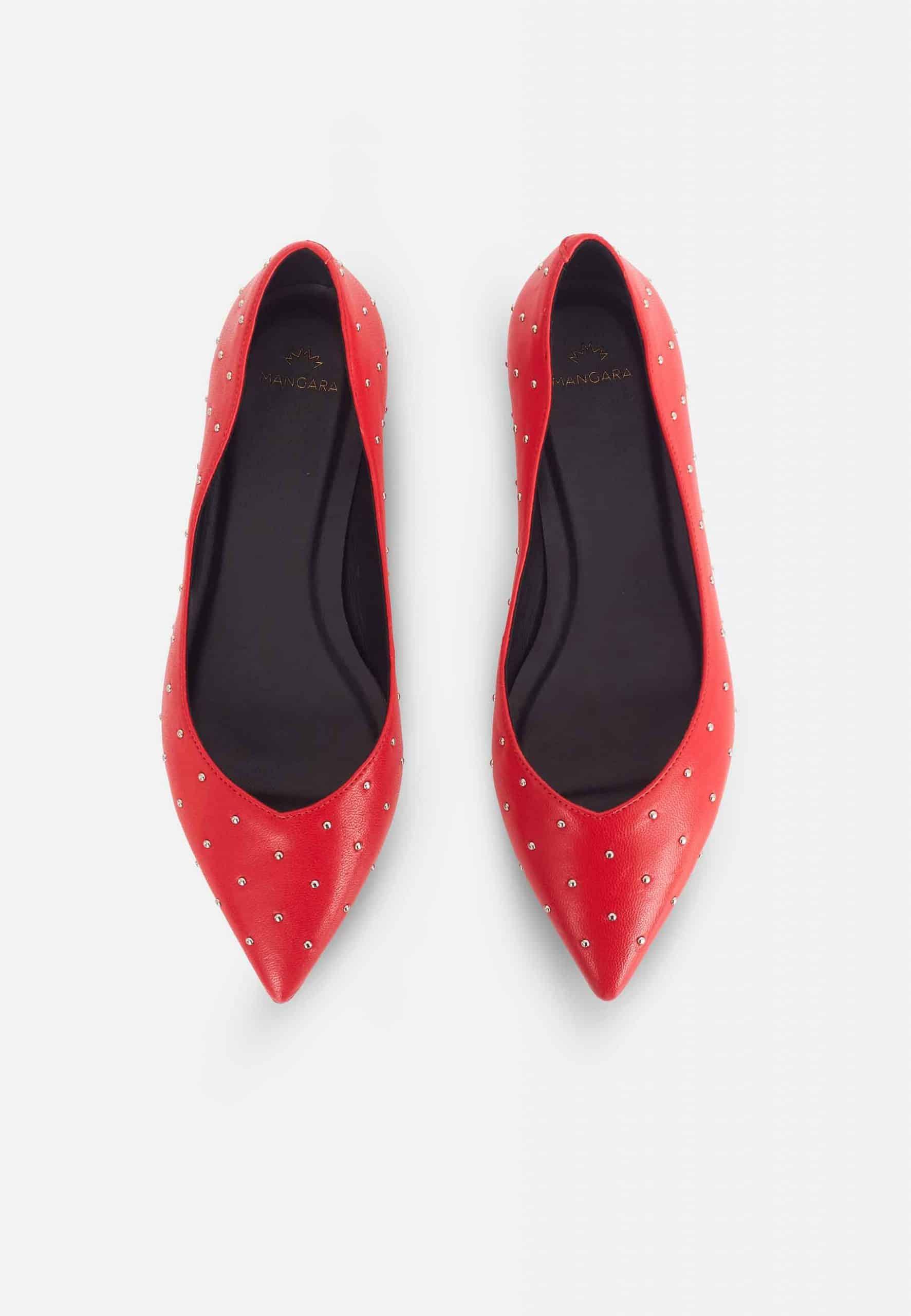 Pair of red pointed-toe shoes with rhinestone details on a light gray background