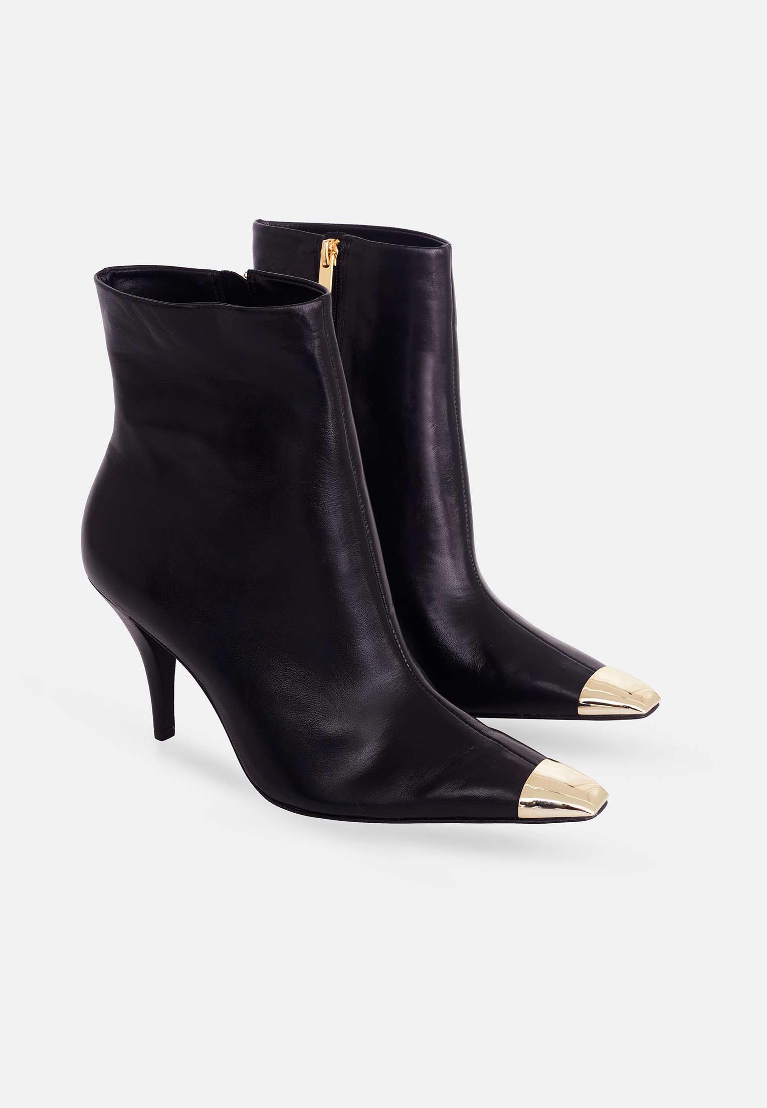 Black ankle boots with gold toes on a white background