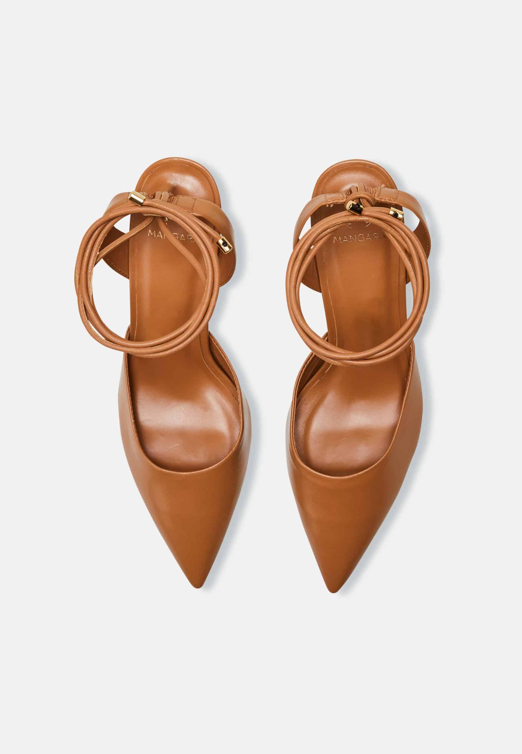 Pair of tan high-heeled shoes with ankle straps on a white background