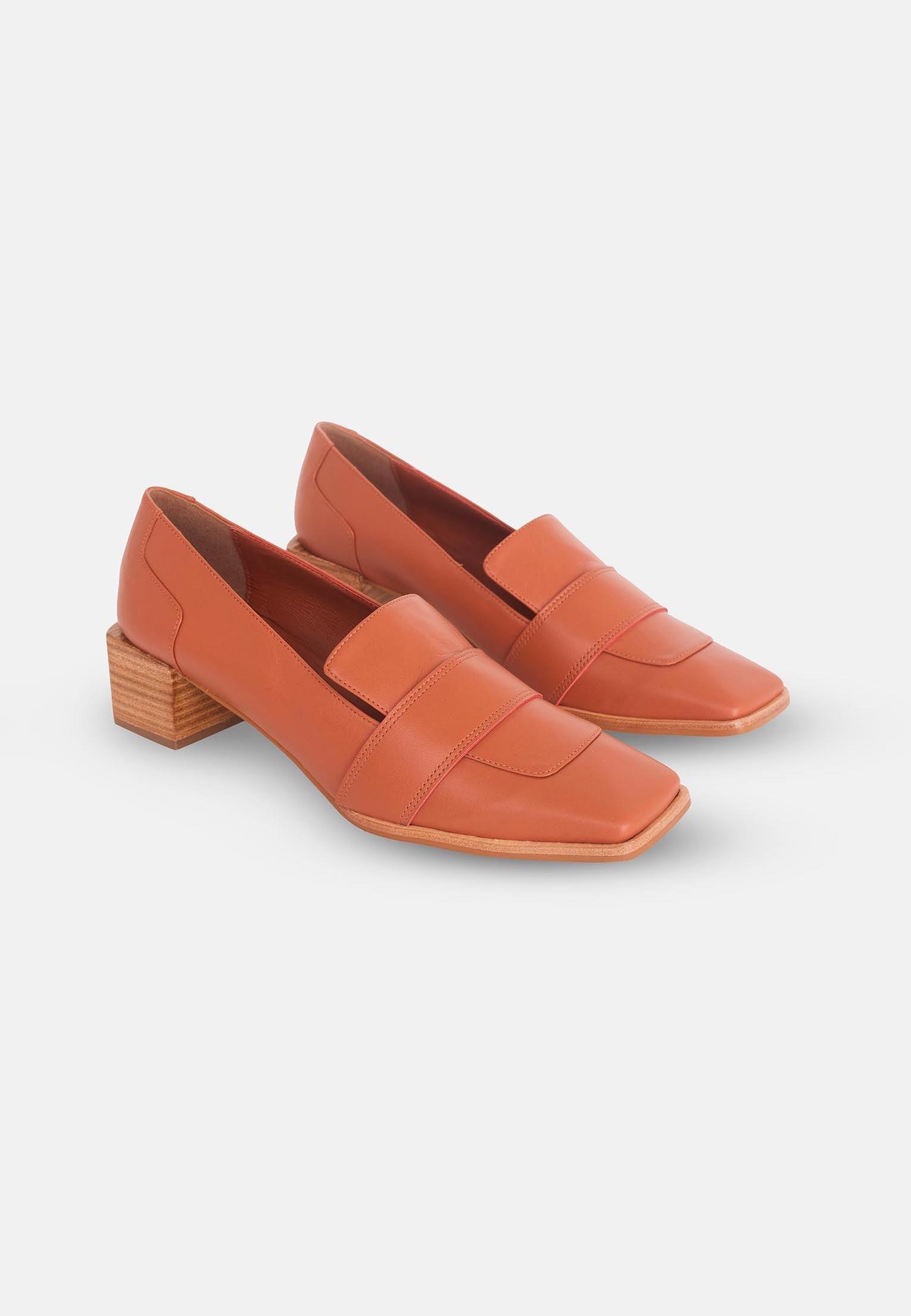 Pair of orange loafers on a light gray background