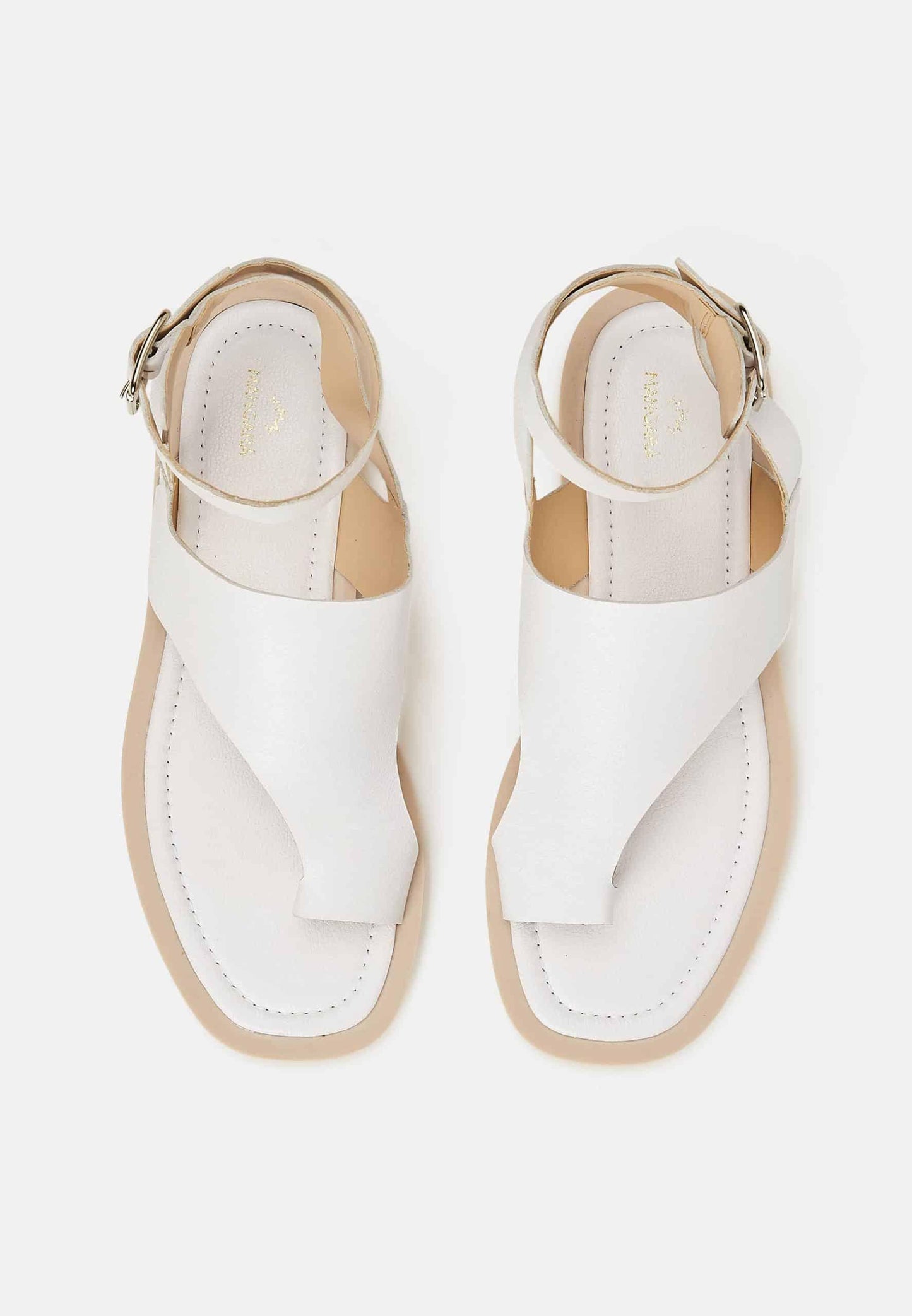 Pair of white sandals with thin straps on a light beige background