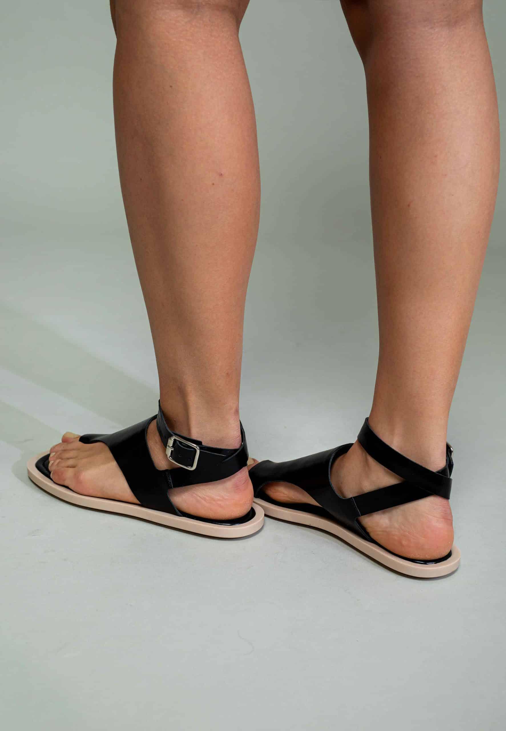 Black sandals worn by a person on a light gray background